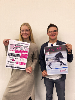 Auf dem Bild sind Das aktuelle Sprecher-Duo des Jugendgemeinderats Sara Weiler und Nico Mößner mit Plakaten aus der JGR-Wahlkampagne zu sehen.