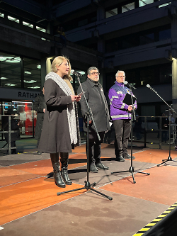 Das Bild zeigt eine Frau und zwei Männer auf einer Bühne vor dem Rathaus Aalen. Die Frau spricht in ein Mikrophon.