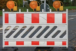 Das Bild zeigt eine Straße, die mit einer rot-weißen Barriere abgespert ist.